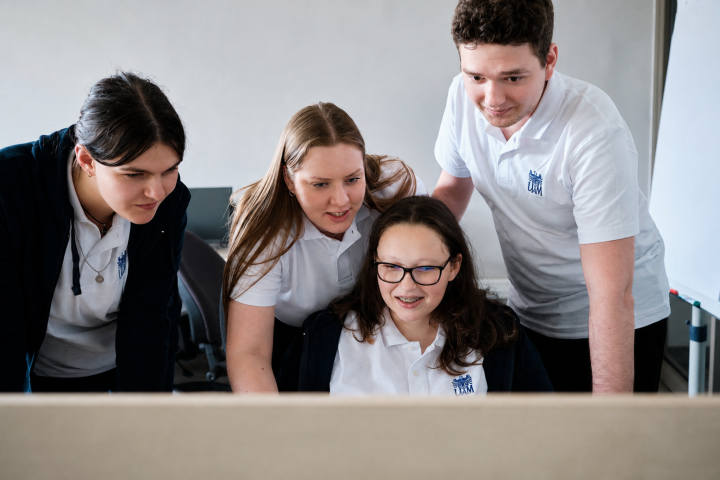 Czworo studentów UAM wspólnie patrzy na ekran komputera.